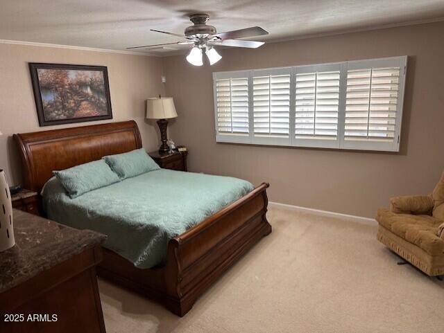 bedroom with light carpet, multiple windows, ceiling fan, and crown molding