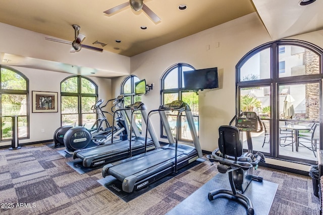 workout area featuring plenty of natural light, a ceiling fan, visible vents, and baseboards