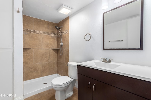 bathroom with a tile shower, tile patterned floors, vanity, and toilet