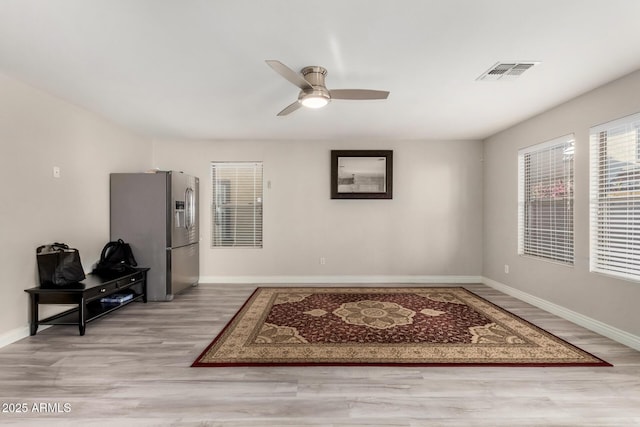 interior space with visible vents, wood finished floors, baseboards, and ceiling fan