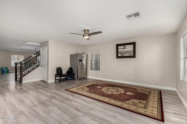 interior space with visible vents, wood finished floors, stairway, baseboards, and ceiling fan