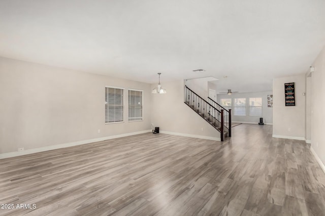 unfurnished living room featuring stairway, visible vents, baseboards, and light wood-style floors