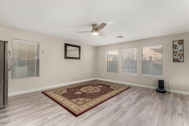 spare room with light wood-type flooring, baseboards, visible vents, and ceiling fan