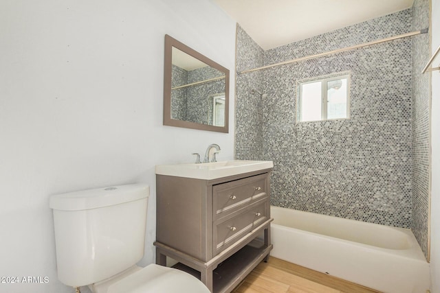 full bathroom featuring tiled shower / bath combo, toilet, wood-type flooring, and vanity