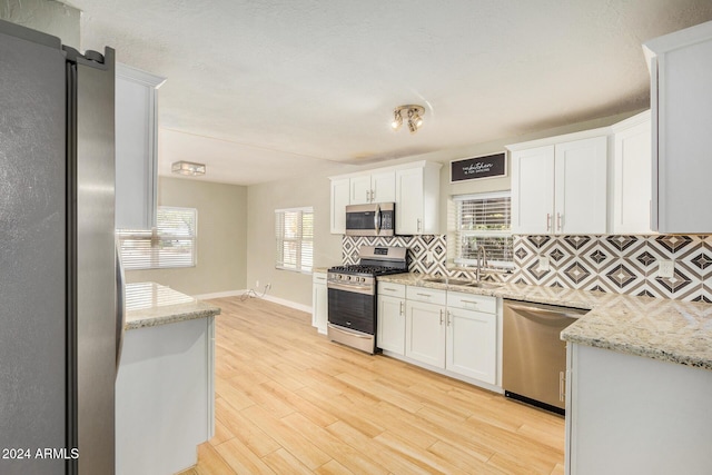 kitchen featuring a wealth of natural light, stainless steel appliances, sink, light hardwood / wood-style flooring, and white cabinetry