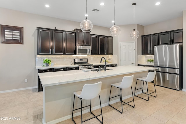 kitchen with appliances with stainless steel finishes, tasteful backsplash, a kitchen breakfast bar, a sink, and recessed lighting