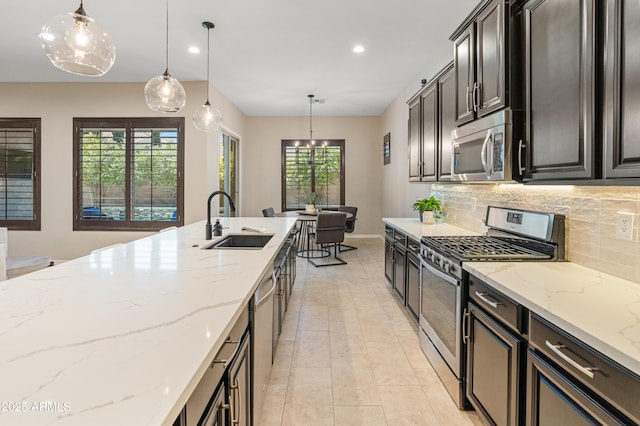 kitchen with appliances with stainless steel finishes, a sink, tasteful backsplash, recessed lighting, and decorative light fixtures