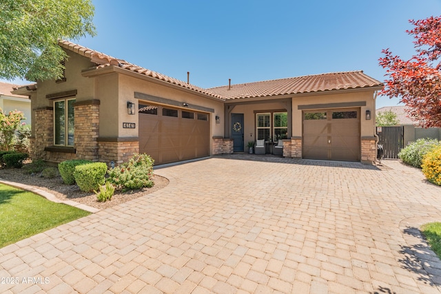 view of front of property with stone siding, an attached garage, decorative driveway, stucco siding, and a tile roof