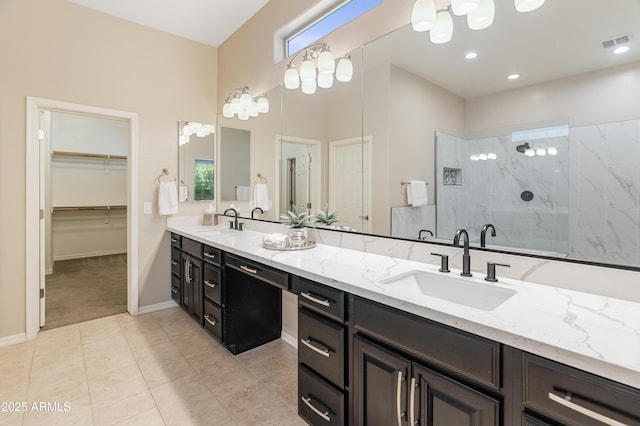 full bath featuring walk in shower, double vanity, a spacious closet, tile patterned floors, and baseboards