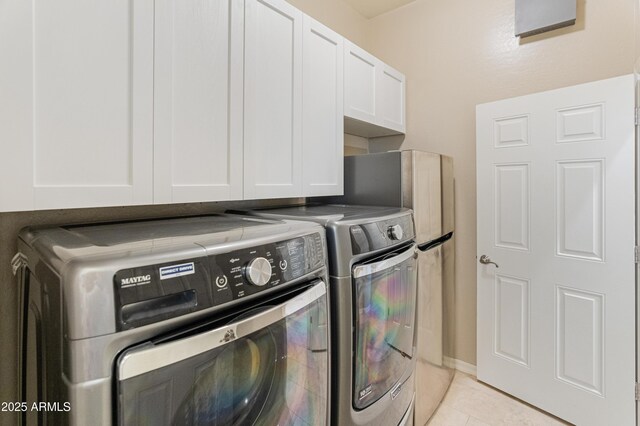 laundry area featuring separate washer and dryer, light tile patterned floors, and cabinet space