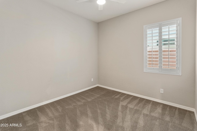 spare room with a ceiling fan, dark colored carpet, and baseboards