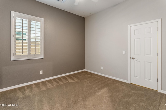 carpeted empty room with ceiling fan and baseboards