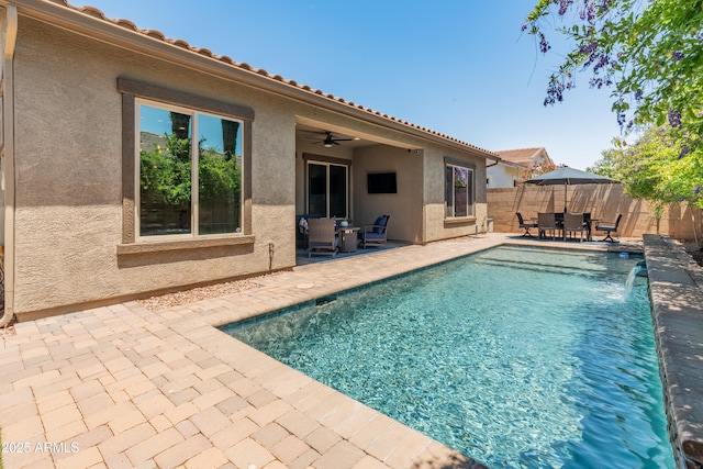view of swimming pool with outdoor dining area, a patio area, a fenced backyard, and ceiling fan