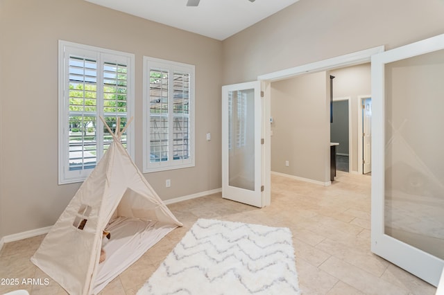 game room with french doors, ceiling fan, light tile patterned floors, and baseboards