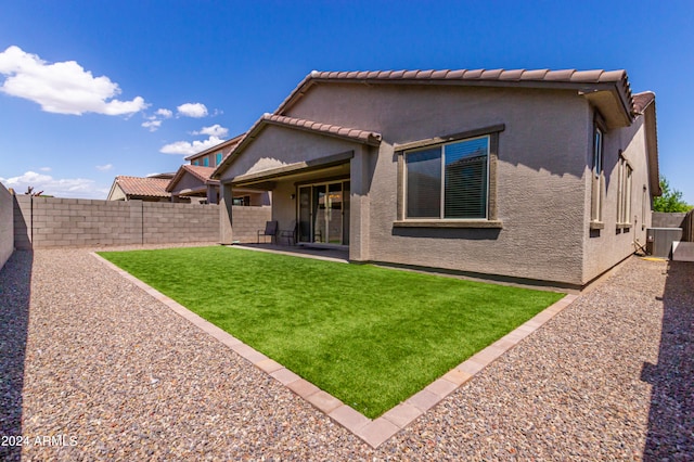 back of property with central AC, a lawn, and a patio