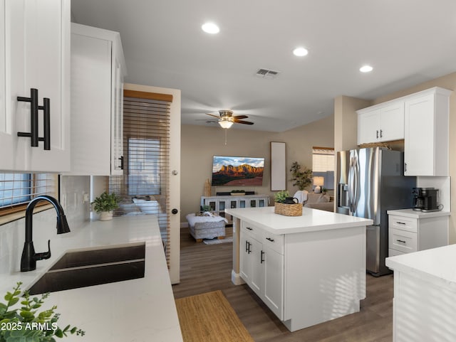 kitchen with wood finished floors, a kitchen island, a sink, visible vents, and stainless steel refrigerator with ice dispenser