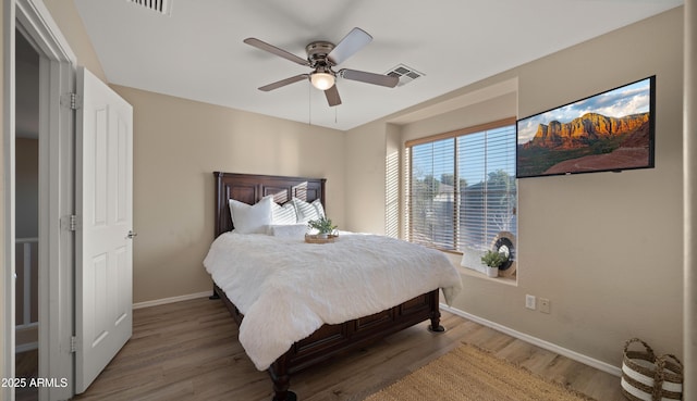 bedroom featuring a ceiling fan, visible vents, baseboards, and wood finished floors