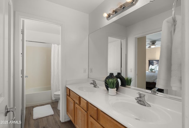 bathroom featuring double vanity, wood finished floors, a sink, and toilet