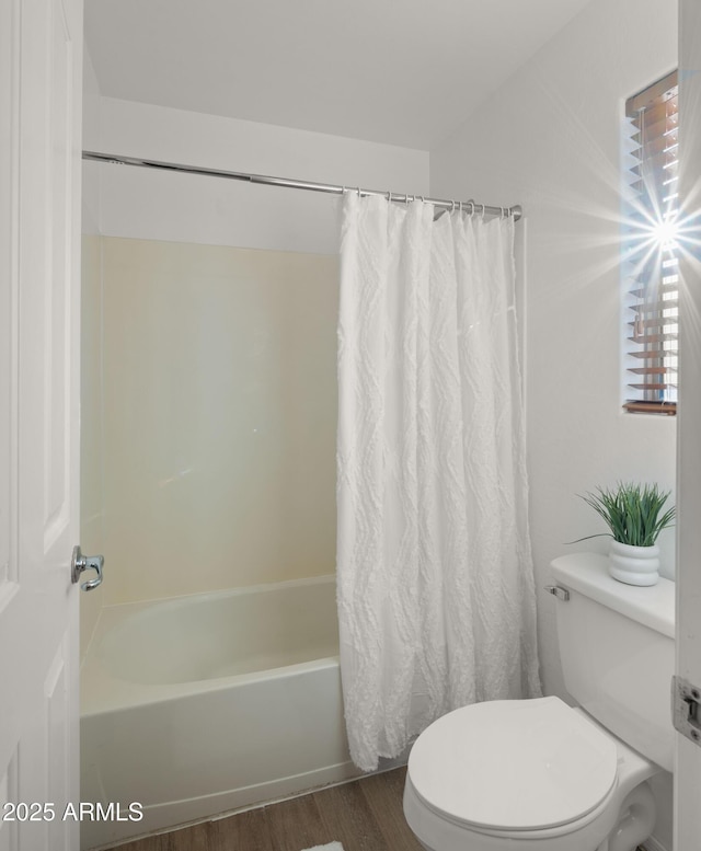 bathroom featuring wood finished floors, toilet, and shower / bathtub combination with curtain