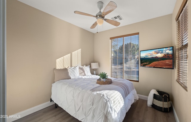 bedroom with a closet, visible vents, baseboards, and wood finished floors