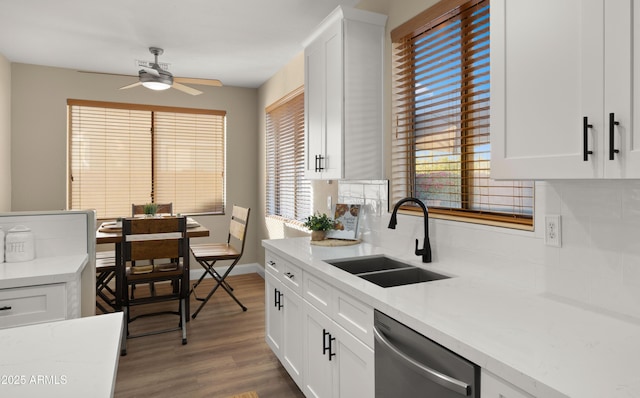 kitchen featuring wood finished floors, stainless steel dishwasher, a sink, and tasteful backsplash