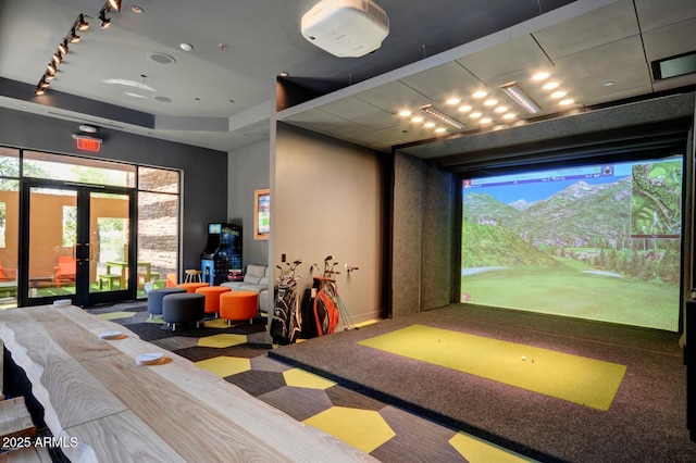 game room featuring golf simulator, french doors, carpet flooring, and track lighting