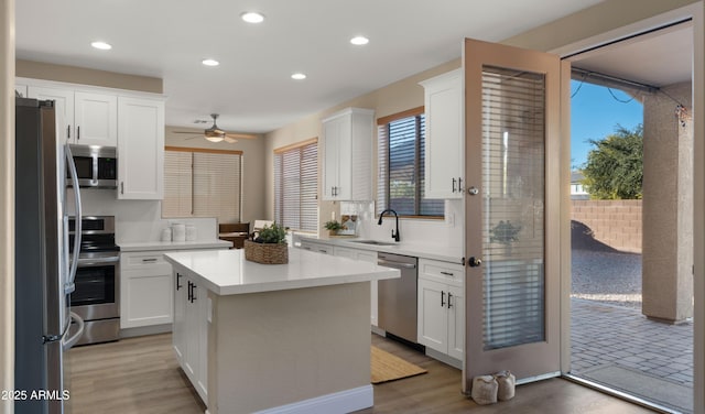 kitchen featuring stainless steel appliances, white cabinets, light countertops, and a sink