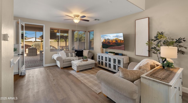 living room featuring a ceiling fan, wood finished floors, visible vents, and baseboards