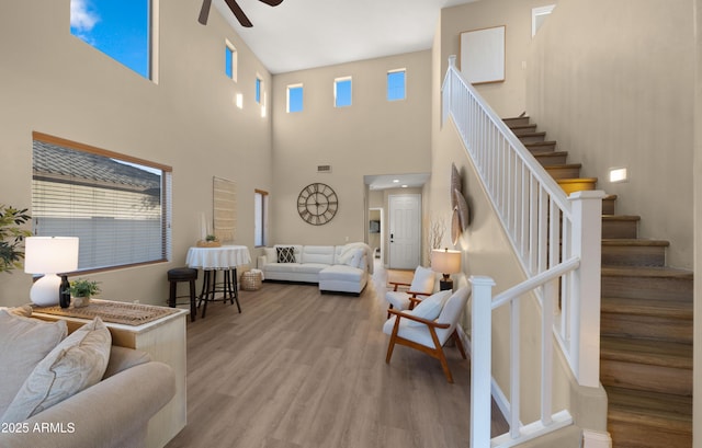 living room with ceiling fan, stairway, wood finished floors, and visible vents