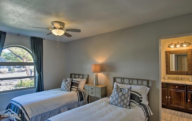 bedroom featuring a ceiling fan, a sink, a textured ceiling, connected bathroom, and light wood finished floors