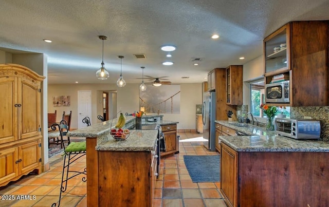 kitchen with a breakfast bar area, visible vents, a kitchen island, a toaster, and appliances with stainless steel finishes