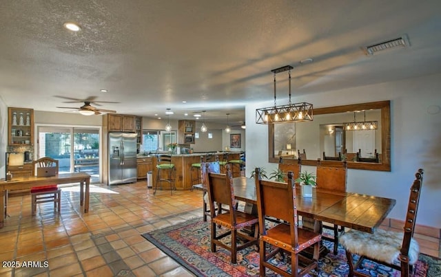 dining area featuring light tile patterned floors, visible vents, a textured ceiling, and a ceiling fan