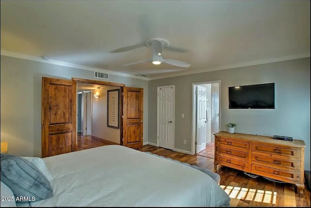 bedroom featuring visible vents, wood finished floors, crown molding, baseboards, and ceiling fan