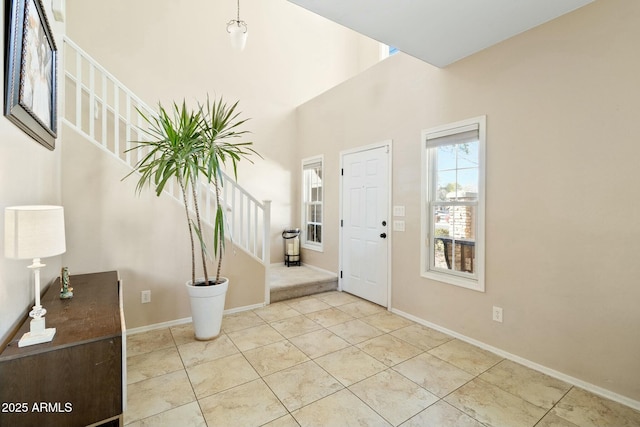 foyer entrance with light tile patterned floors and a towering ceiling