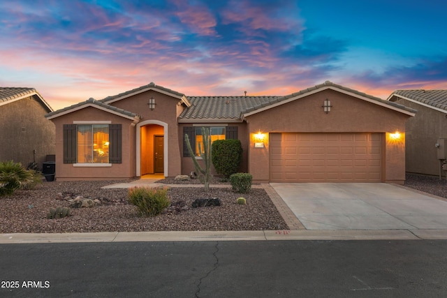 ranch-style home with a tile roof, concrete driveway, a garage, and stucco siding