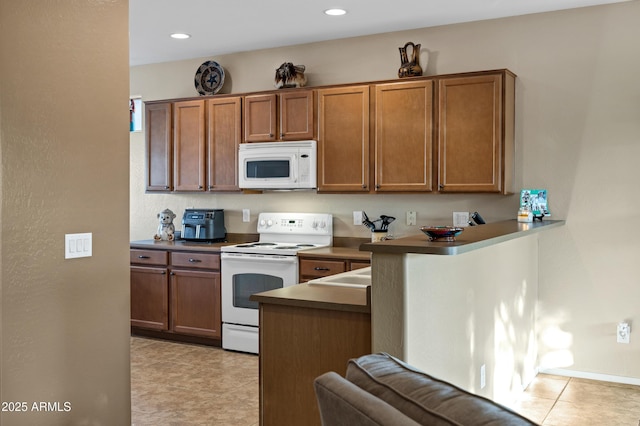 kitchen with white appliances, dark countertops, recessed lighting, and brown cabinetry