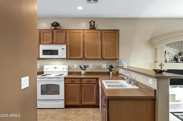 kitchen with brown cabinetry, white appliances, a peninsula, and a sink