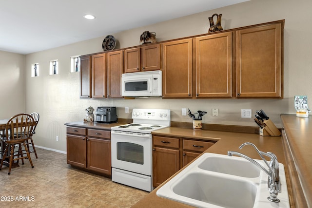 kitchen featuring light tile patterned floors, recessed lighting, brown cabinetry, white appliances, and a sink