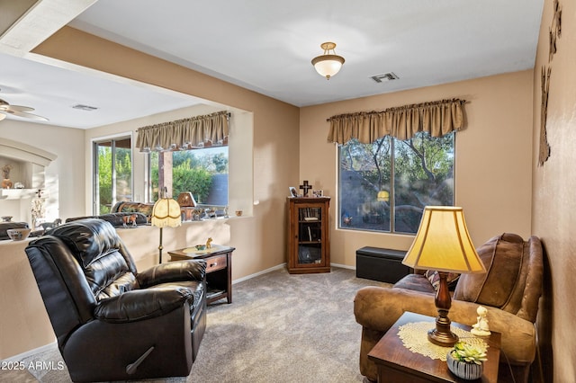 carpeted living room featuring visible vents, a ceiling fan, and baseboards