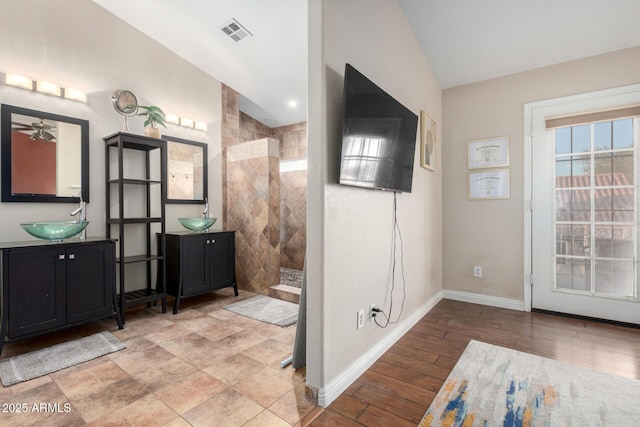 bathroom featuring a tile shower, vanity, hardwood / wood-style flooring, and vaulted ceiling