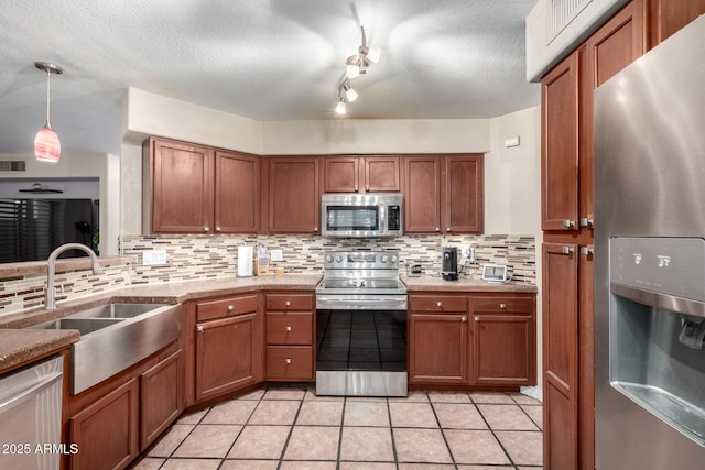 kitchen featuring sink, hanging light fixtures, stainless steel appliances, tasteful backsplash, and light tile patterned flooring