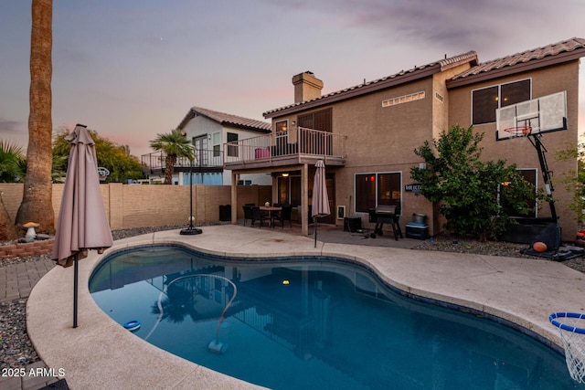 pool at dusk featuring a patio