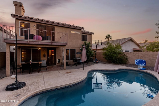 pool at dusk featuring grilling area and a patio area