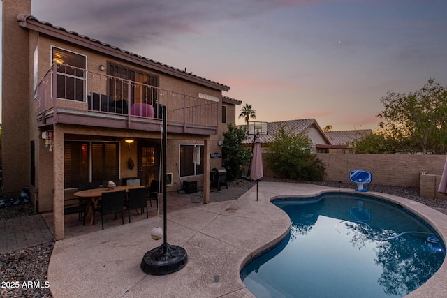 pool at dusk featuring grilling area and a patio area