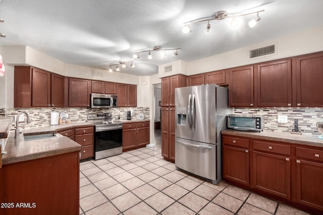 kitchen featuring appliances with stainless steel finishes, tasteful backsplash, sink, light tile patterned floors, and a textured ceiling