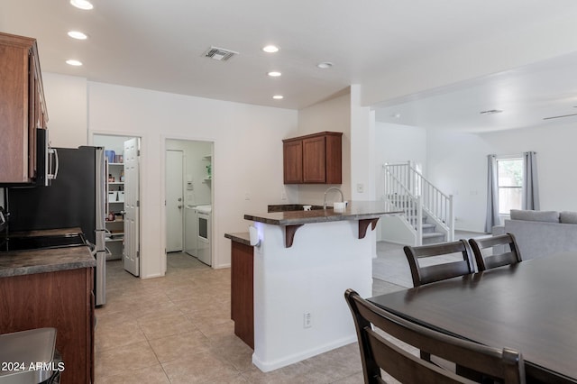 kitchen with a kitchen breakfast bar, sink, ceiling fan, light tile patterned floors, and kitchen peninsula