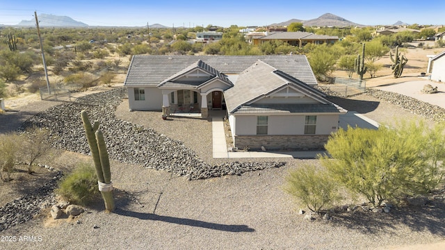 view of front of home featuring a patio, stucco siding, a mountain view, stone siding, and a tiled roof