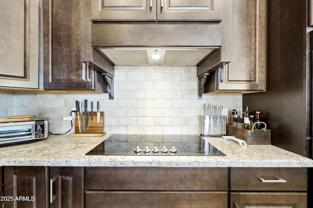 kitchen with light stone counters, dark brown cabinets, and black electric cooktop