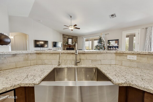 kitchen with light stone counters, a sink, and a ceiling fan