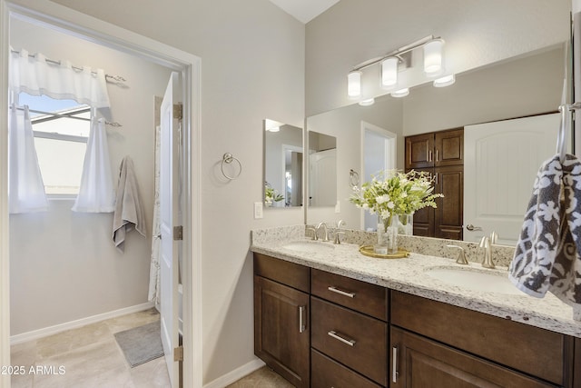 bathroom featuring double vanity, a sink, and baseboards